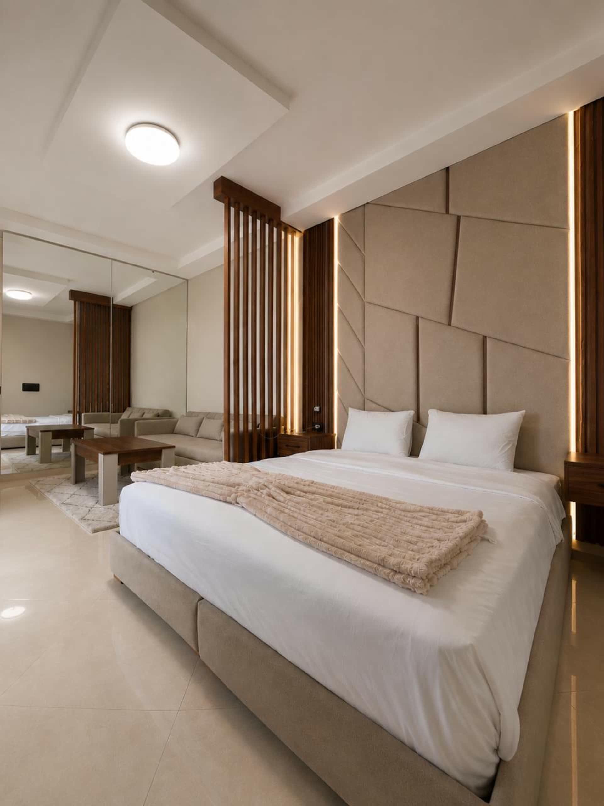 King-size bed with a padded headboard and wooden screen
